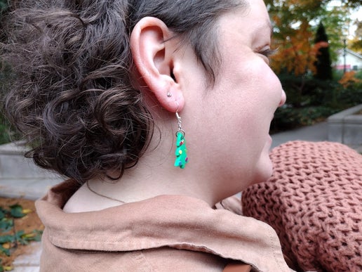Woman wearing Christmas tree earrings with rainbow colored ornaments