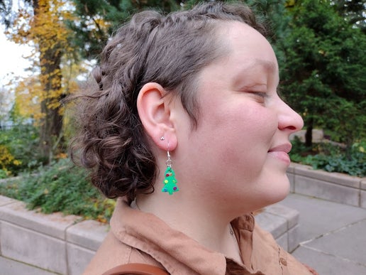 Woman wearing Christmas tree earrings with rainbow colored ornaments