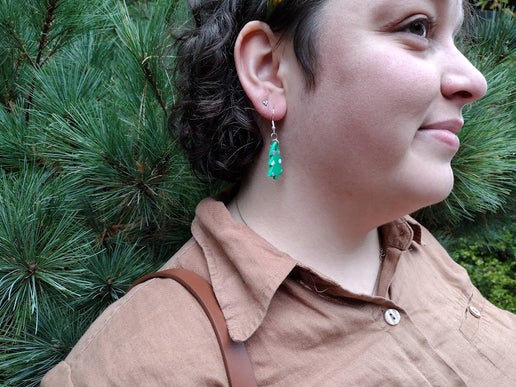 Woman wearing trans pride tree earrings